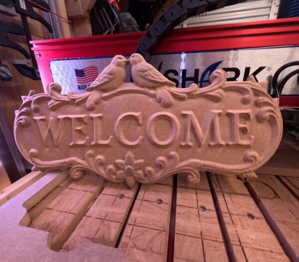 Welcome Sign with Doves CNC carving displayed on workbench after machining