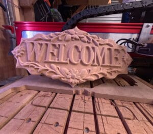 Floral Welcome Sign CNC carving on a wooden workbench in workshop